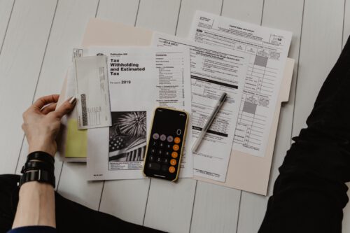 Tax forms, calculator, and pen spread out on a table
