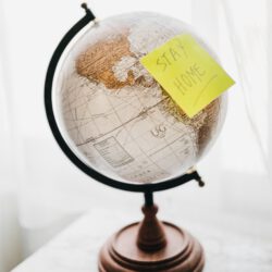a globe with "stay home" post-it