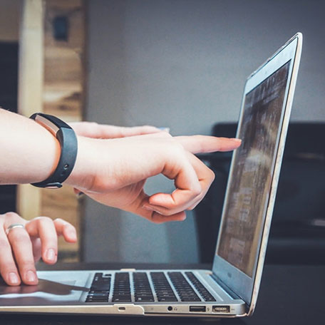 Hands pointing to laptop screen, collaborating on financial strategy